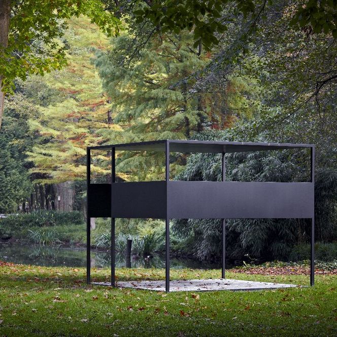 Umgeben von Bäumen und Grün steht ein schwarzer Metallpavillon