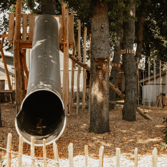 Der Spielplatz des Hofes mit silberner Tunnelrutsche