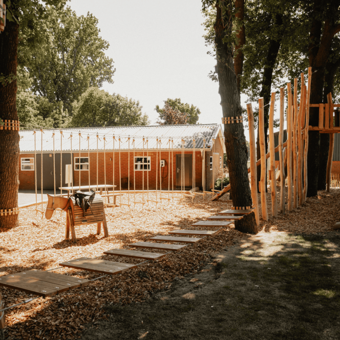 Spielplatz des Hofes mit Spielgeräten und Teilen des Tiefseilgartens